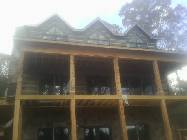 Dormers and porch framing on a large log home under construction — Roof Coating work by our crew in North Chili