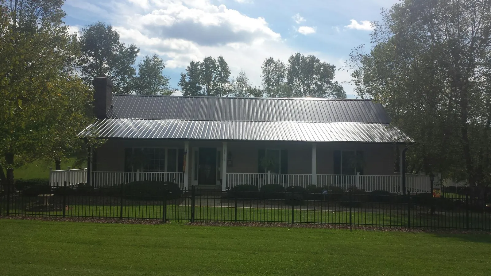 Gray metal roof on a brick ranch with a full width front porch — Gutter Guard Installation work by our crew in North Chili