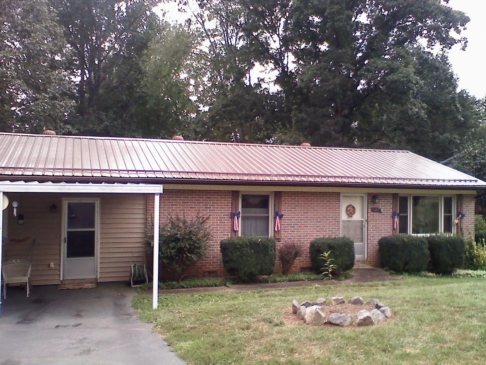 Bronze metal roof and carport on a brick ranch home — Roof Repair work by our crew in North Chili