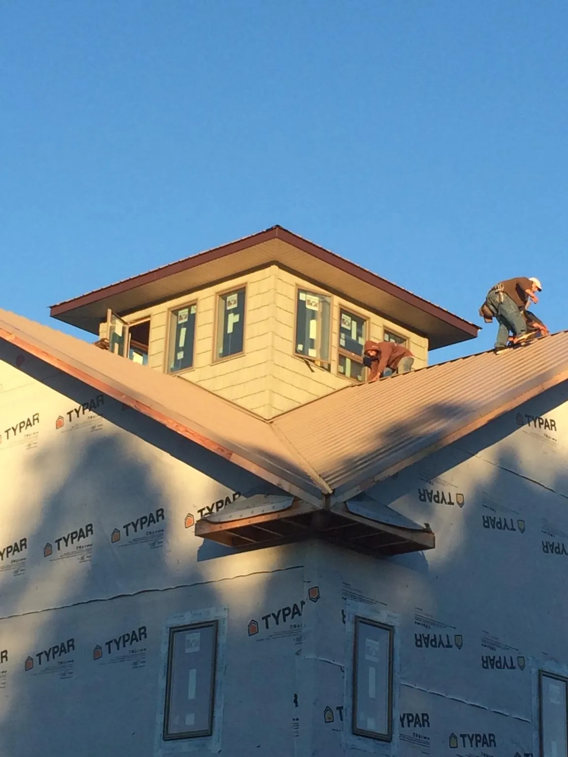 Roofers working around a rooftop cupola on a new metal roof at sunset — Roof Waterproofing in North Chili by Roofing Brothers